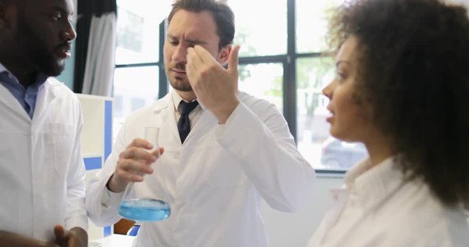 Diverse Team Of Scientists Analyzing Smell Of Liquid In Flask Working In Laboratory Making Experiments Mix Race Group Of Researchers Slow Motion 60