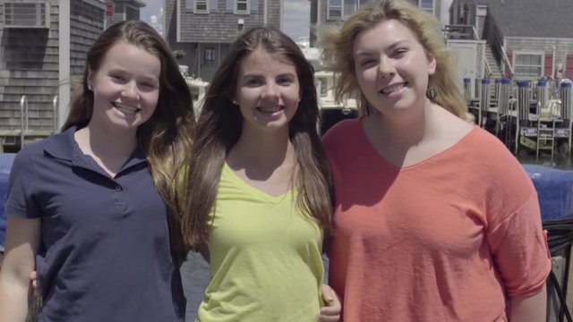 Fun Group Of Teen Girls Pose For Portrait On A Town Pier, They Make Funny Faces And Poses 