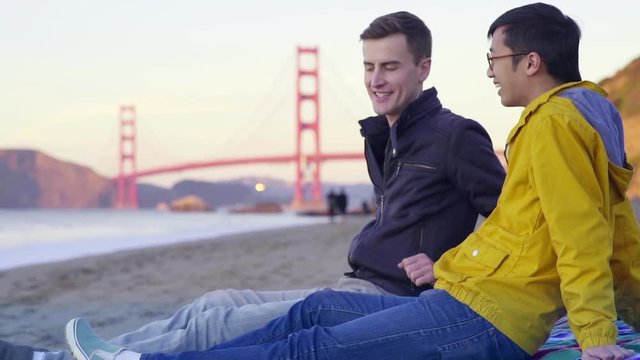 Mixed Race Gay Couple Take A Photo Together On The Beach With The Golden Gate Bridge In The Background
