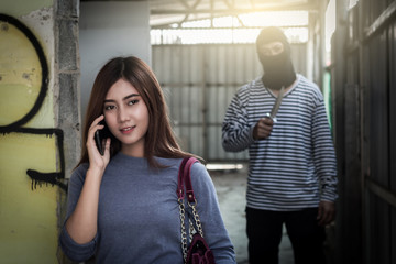 Beautiful young woman talking on smartphone and being stalked by man criminal with the knife
