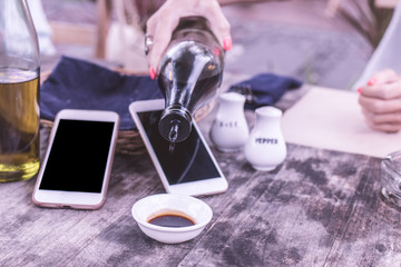 Pouring soy sauce in cafe. Smartphone wit black screen empty space on a background.