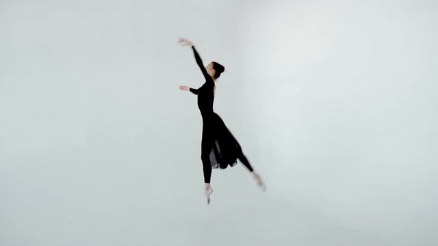 A ballet dancer 20s girl in black dress and white pointe elegantly dances in a white dancing class slow motion 120fps 1080p.