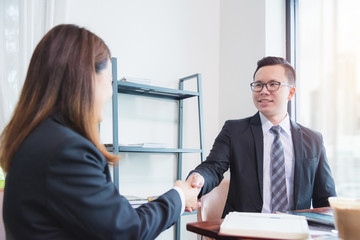 Businessman shaking hand with businesswoman in office