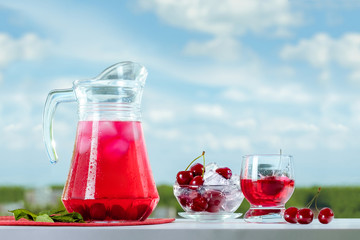 Fresh cool drink from a cherry. Cherries on ice. Summer still life against the sky.