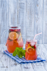 Dietary detox drink with lemon juice, red strawberry and mint leaves in clear water with ice