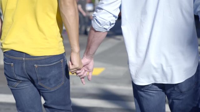 Closeup Of Gay Couple Holding Hands And Walking Across The Street In City