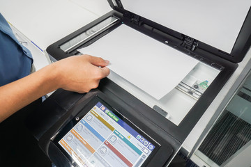 businessman in blue shirt put paper sheet onto printer scanning