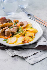 Pork stewed with apples with potatoes for garnish on plate on gray table background. Meat for lunch/dinner
