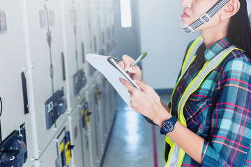 women engineer working on checking and maintenance electrical equipment ;women engineer checking status switchgear with checklist
