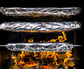 Spießbraten in Alufolie dreht sich an einem Industriegrill