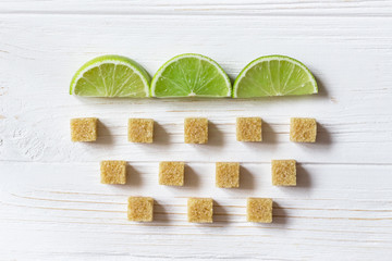 Lime slices and cubes of brown sugar. Cloud with rain. Ingredients for Mojito on wooden white background. Flat lay.