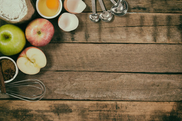 Bakery background comprise apples,wheat flour,egg and cinnamon on rustic wood table with copy space.Prepare ingredient for baking apple cake on wood table. Top view bakery background concept.
