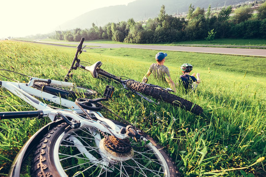 Father and son rest together in high green grass after bicycle walk