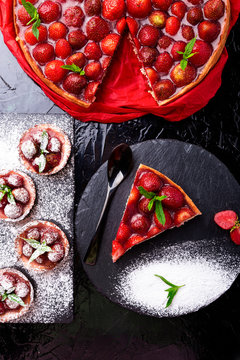Strawberry pie and tart on black slate plate. Mix desserts. Top view.