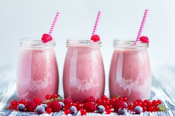 Several glass transparent jars with purple yogurt in them mixed with berries.