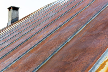Old rusty iron metal roof with chimney