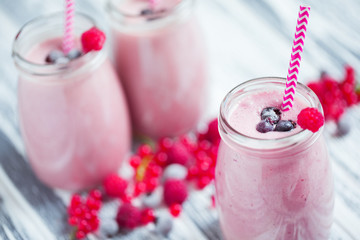 Close up of three jars of yogurt with cranberries strawberries and blueberries standing on table.