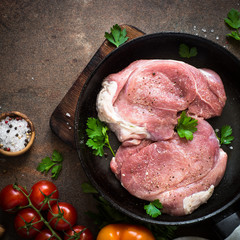 Raw pork meat in the pan. Top view copy space stone background.