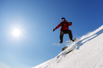 Naklejka na ściany i meble Snowboarder jumping from the springboard against the sky