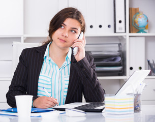 Female is working at a computer and talking phone