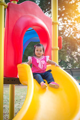 Fototapeta na wymiar Toddler girl playing on a slide at children playground