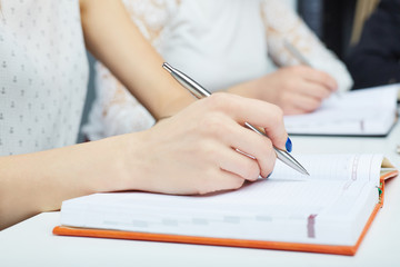 Close up image of woman's hand making notes at a business meeting.