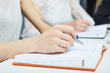 Woman's hand making notes at a business meeting closeup. Business job offer, financial success, certified public accountant concept.