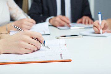 Female hand holding silver pen closeup. Woman writing plan, making notes on business meeting.