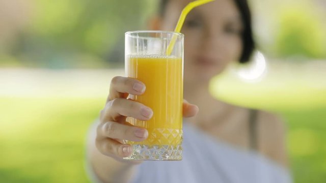 Fresh orange glass of juice in a woman's hands, she give healthy drink