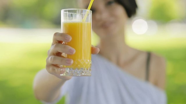 Fresh orange glass of juice in a woman's hands, she give healthy drink