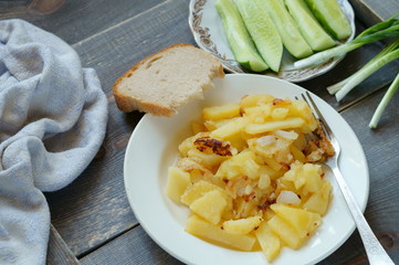 Fried potatoes on a white plate with cucumbers