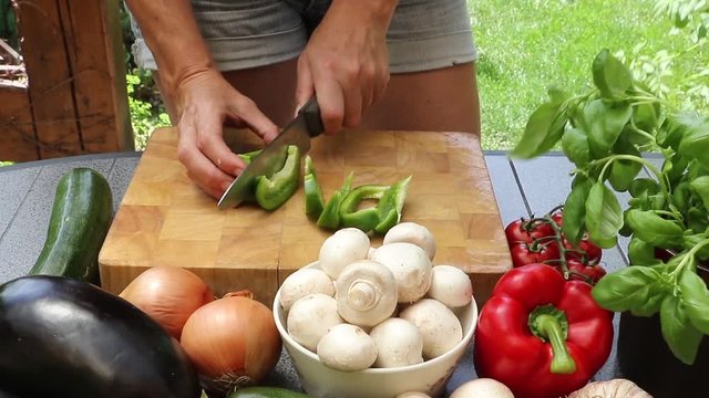 Woman cutting green pepper on a wooden board
