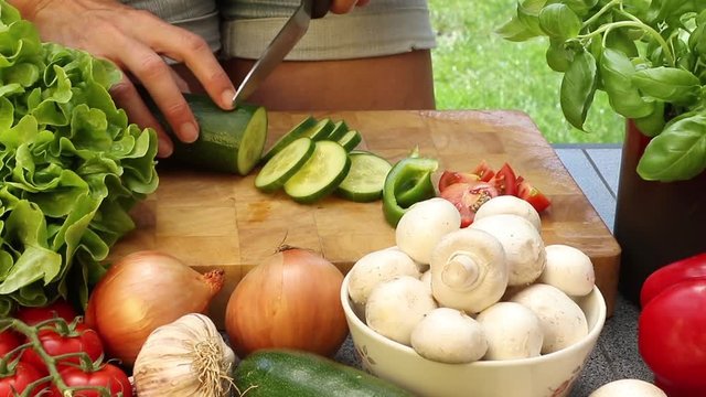 Woman cutting cucumber on a wooden board