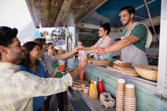 Waitress and waiter giving juice to customer at counter