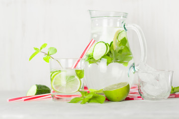 Detox water in a glass jug and a glass. Berries and lime, red and green. Fresh mint leaves.