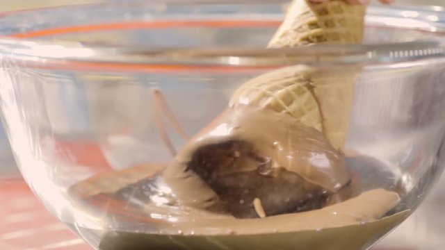 Woman Dips A Sugar Cone Into A Glass Bowl Of Chocolate, She Spins The Cone To Shake Off Excess Chocolate