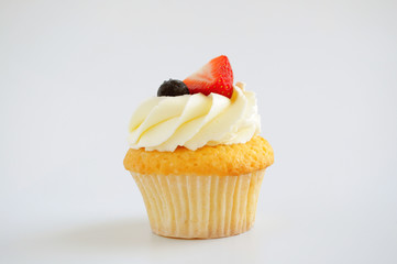 Cupcake with whipped cream, fresh strawberry, blueberry on white background. Picture for a menu or a confectionery catalog.
