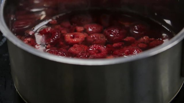 Pot with compote of fresh berries on stove. Cooking homemade jam