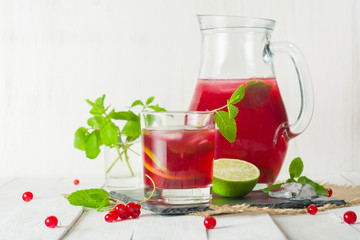 Compote in a glass jug and a glass. Berries and lime, red and green. Fresh mint leaves. Copy space.