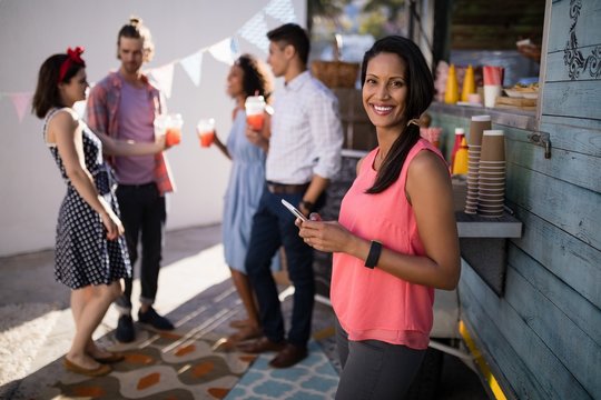 Beautiful Woman Using Mobile Phone Near Food Truck