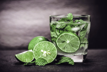 Close up the fresh mojito cocktail with fresh lime and mint leaf on black stone background