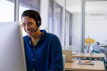 Male executive in headset working over computer at his desk