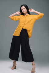 attractive brunette woman posing in yellow blouse, isolated on grey