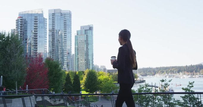 Business woman walking drinking coffee in Vancouver Canada. Businesswoman doing walk in Vancouver harbour. Mixed race Asian Chinese / Caucasian young urban professional in her 20s.
