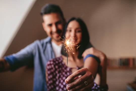 Young couple celebrating with sparkler at home