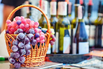 Grapes in a basket on the background of bottles of wine