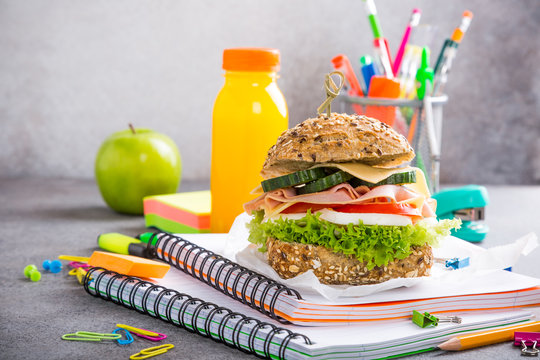 Healthy lunch for school with sandwich, fresh apple and orange juice. Assorted colorful school supplies. Copy space.