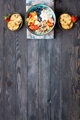 Healthy breakfast, cereal with yogurt, strawberries, blueberry, apple, banana, on rustic wooden.  Top view