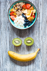 Healthy breakfast, cereal with yogurt, strawberries, blueberry, apple, banana, on rustic wooden.  Top view