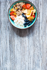 Healthy breakfast, cereal with yogurt, strawberries, blueberry, apple, banana, on rustic wooden.  Top view